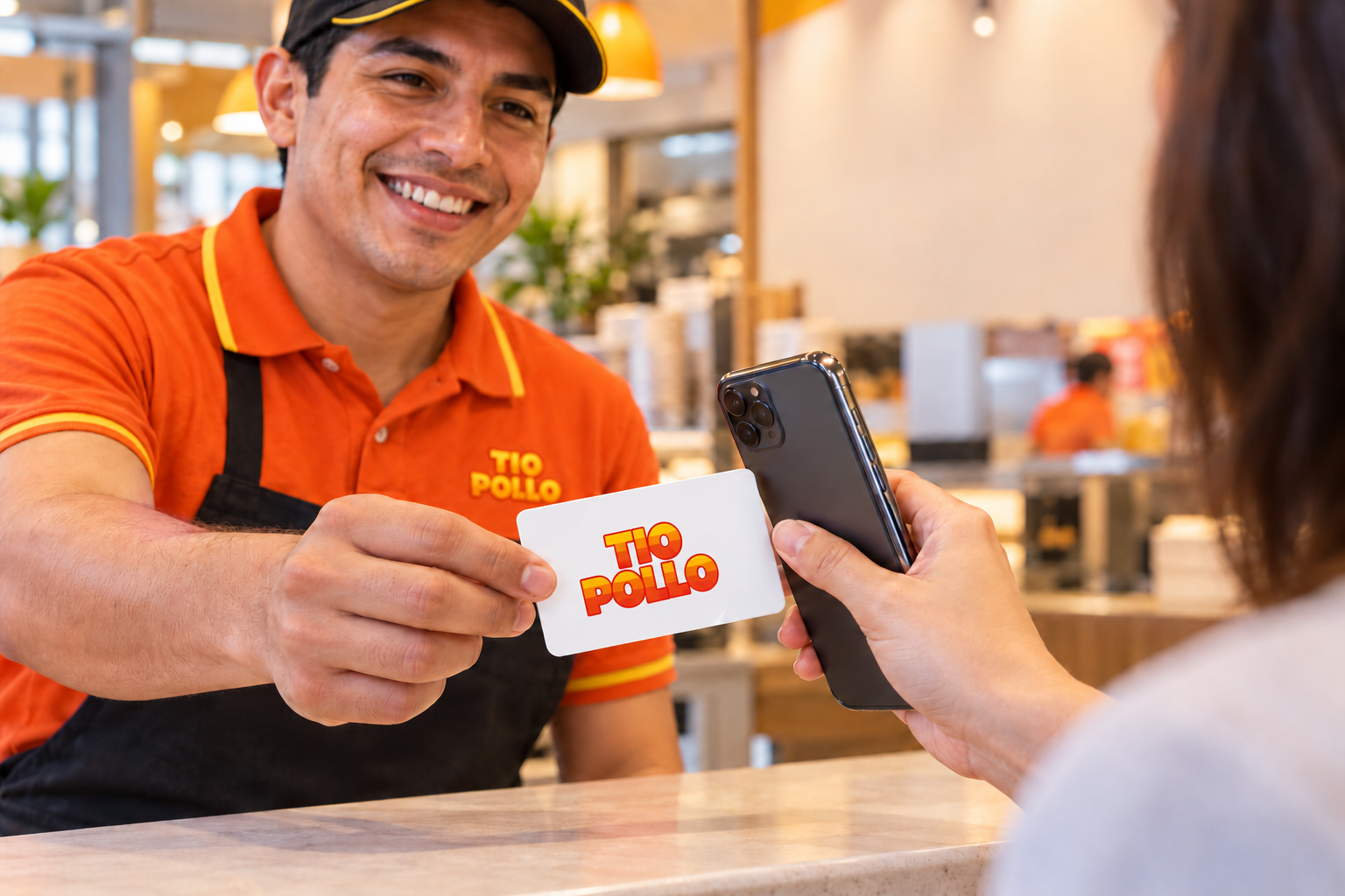 Personal de restaurante muestra una tarjeta personalizada mientras el cliente acerca su teléfono